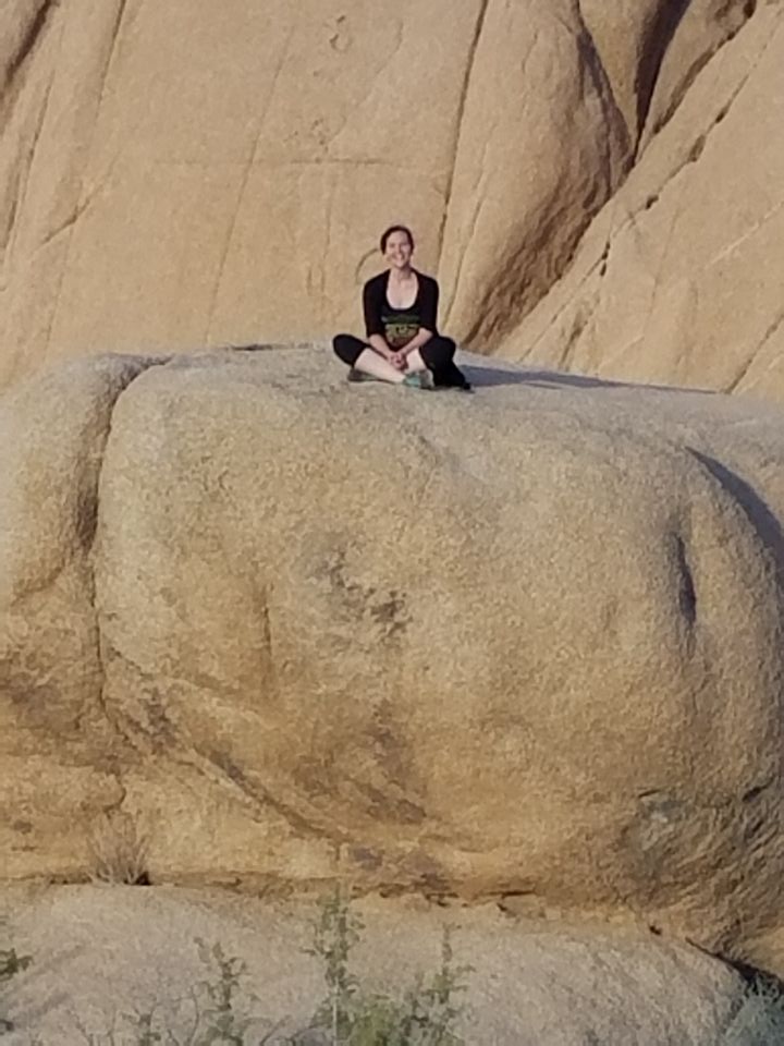 Chantelle sitting on a large boulder in Joshua Tree National Park